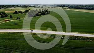 Aerial view of  a rural landscape featuring a long road winding through a lush green