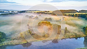 Aerial view of rural landscape with river and lush trees in fog