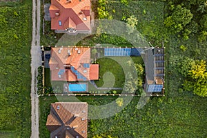 Aerial view of rural residential area with private homes between green fields at sunrise