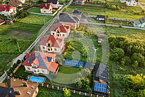 Aerial view of rural residential area with private homes between green fields at sunrise