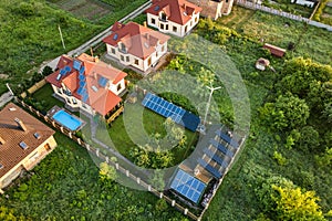 Aerial view of rural residential area with private homes between green fields at sunrise