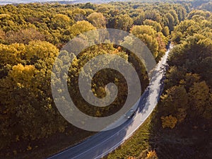 Aerial view of rural road with car in yellow and orange au