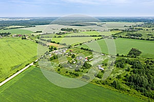 Aerial view of rural village among green fields in sunny summer day