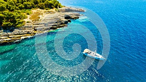 Aerial view on sail yacht, rocks and forest. Sea coastline. Vacation and adventure. Rocks and turquoise water.