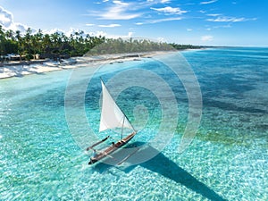 Aerial view of the sailboat on blue sea, empty white sandy beach