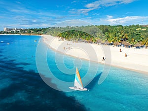 Aerial view of the sailboat on blue sea with white sandy beach