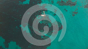 Aerial view of a sailboat floating on the blue waters of the ocean near Sa Coma in Mallorca, Spain