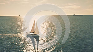 Aerial view of a sailing yacht at sea against blazing sun