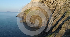 Aerial view of Salina coast. Huge cliff in a summer sunset. green bushes on mountain slope, little village in the valley