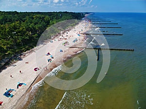 Aerial view on sand beach, breakwaters, forest and sunbathers photo