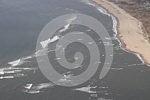 Aerial view of the sand sea beach and shallow water with waves.