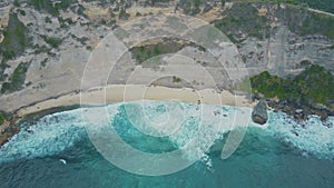 Aerial view of sandy beach with beautiful waves, turquoise ocean water, palms