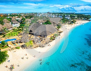 Aerial view of sandy beach, blue sea, bungalows, palms, umbrellas