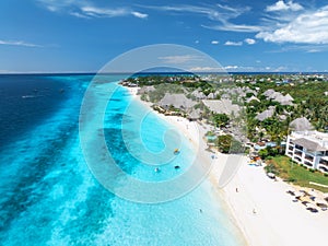 Aerial view of sandy beach, blue sea, bungalows, palms, umbrellas