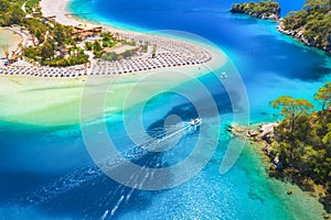 Aerial view of sandy beach, blue sea and speed boat at sunny day