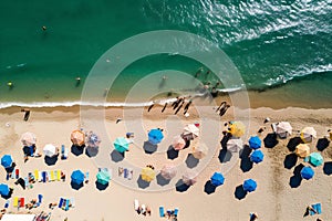 Aerial view of sandy beach with colorful umbrellas, swimming people in sea bay with transparent blue water in summer