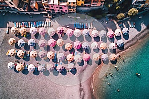 Aerial view of sandy beach with colorful umbrellas, swimming people in sea bay with transparent blue water in summer