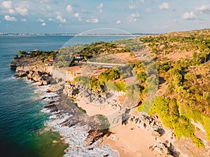 Aerial view of sandy beach with ocean and rocks in Bali.