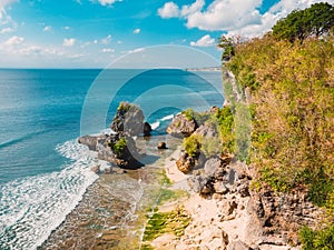 Aerial view of sandy beach with ocean and rocks at Padang Padang, Bali.