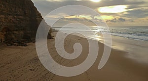 Aerial view from a couple walking sandy beach at the sunset with an amazing cliff