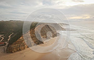 Aerial view from a sandy beach at the sunset with an amazing cliff