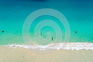 Aerial view of sandy beach with tourists swimming in beautiful clear sea water