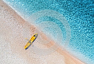 Aerial view of sandy beach with yellow canoe and blue sea