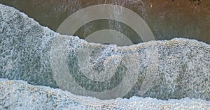 Aerial view of a sandy coastal section with approaching breaking waves