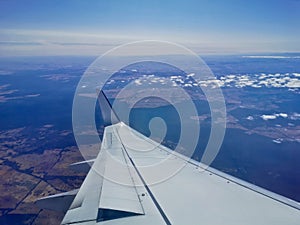 Aerial view scene from the left wingside of aeroplane flying in sunny day with blue sky