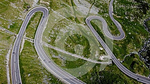 Aerial view of a scenic road winding through a lush landscape of trees and green grass in Romania