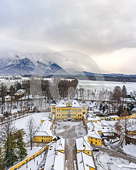 Aerial view of Schloss Hellbrunn covered in snow with view of Untersberg near Salzburg Outskirts in winter time