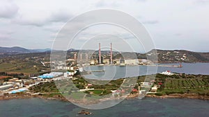 Aerial view of sea bay with old factory and a small white church, low vegetation mountains, Lavrio Greeceside, side movement by dr