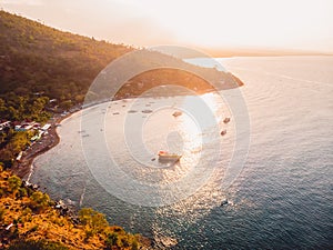 Aerial view of sea with mountains and local boats in Amed, Bali with sunset lights photo