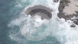 Aerial view sea waves breaking rocks on a cloudy day