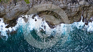 Aerial view of sea waves crashing on rocks cliff in the blue ocean. Top view of coastal rocks in Phuket ocean. Landscape view