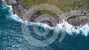 Aerial view of sea waves crashing on rocks cliff in the blue ocean. Top view of coastal rocks in Phuket ocean. Landscape view