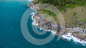 Aerial view of sea waves crashing on rocks cliff in the blue ocean. Top view of coastal rocks in Phuket ocean. Landscape view