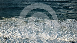 Aerial view of sea waves and dark blue beach