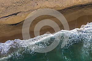 Aerial view of sea waves and a remote secluded sandy beach