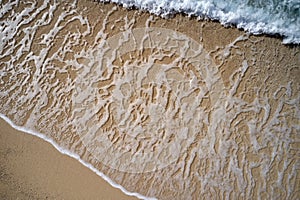 Aerial view of sea waves and sandy beach.