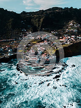Aerial view of sea waves washing rocky beach with buildings in Ponta do Rosto photo