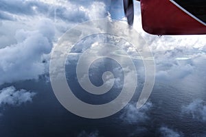 Seaplane flying through the clouds over Maldive island ocean