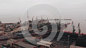 Aerial view of seaport with tower cranes and tankers next to railroad for cargo transportation