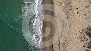 Aerial view of a secluded sandy beach and sea waves