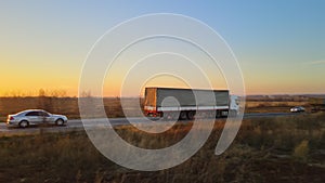 Aerial view of semi-truck with cargo trailer driving on highway hauling goods in evening. Delivery transportation and