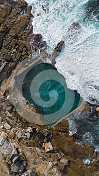 Aerial view of a serene swimming pool by large rocky cliffs: Mahon Pool, Maroubra, Sydney, Australia