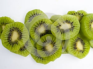 Aerial view of several slices of green kiwis on a white background