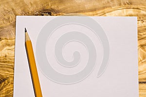 Aerial view of a sheet of paper with a yellow pencil on a wooden