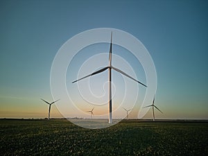 Aerial view of a silhouette wind turbine standing in a wheat field at night time.