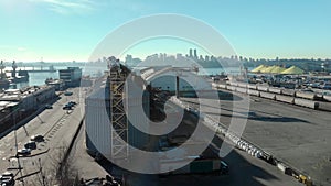 An aerial view of silos in the North Vancouver cargo terminal and trainyard with a view of downtown Vancouver.